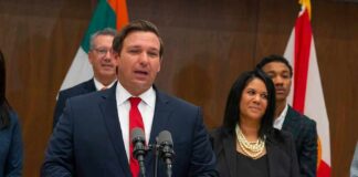 Ron DeSantis speaking at a podium with Chi Onwurah standing behind him