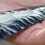 Hand holding a flaked obsidian blade