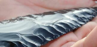 Hand holding a flaked obsidian blade