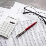 Calculator, pen, and eyeglasses on financial spreadsheets