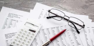 Calculator, pen, and eyeglasses on financial spreadsheets