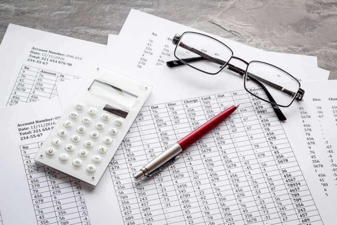 Calculator, pen, and eyeglasses on financial spreadsheets