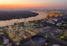 Saudi Oil Hub Hit by Drone Strikes Industrial oil refinery complex beside a river at dusk