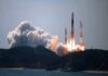 Rocket lifts off from coastal launch site with smoke and flames