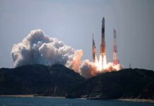 Rocket lifts off from coastal launch site with smoke and flames