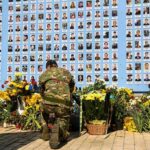 Israel Holds State Memorial for October 7 Victims Soldier kneels at memorial wall with photos and flowers