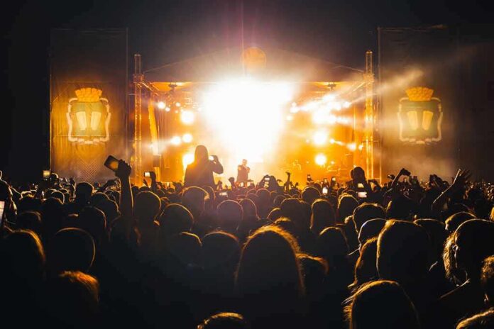 shutterstock_1971943841-1 Crowd at a nighttime concert with bright stage lights