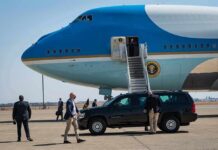 Trump Rally Targets Cooper Over Inmate Releases Security detail near blue and white aircraft with staircase and SUV