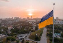 Ukrainian flag flying over a city at sunset