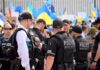 28 Charged in California Voter Fraud Cases Police officers stand among a crowd with blue and yellow flags