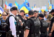 Police officers stand among a crowd with blue and yellow flags