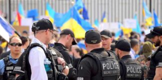 Police officers stand among a crowd with blue and yellow flags