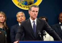 Gavin Newsom at a podium during a press conference with officials behind him