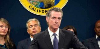 Gavin Newsom at a podium during a press conference with officials behind him