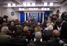 Trump Rejects Talk of Wiles’ Exit Press secretary at podium addressing reporters in briefing room