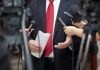 Trump Pays Tribute to Bears Legend Man in suit with red tie speaking to reporters holding microphones